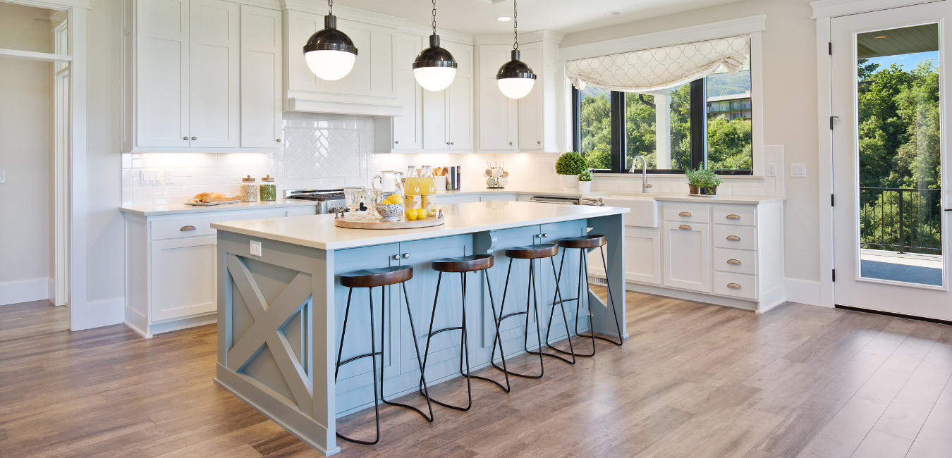 Bright white kitchen with a blue island, pendant lighting, and wood floors